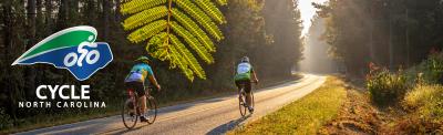 Cyclers on the roadway with the Cycle NC Logo